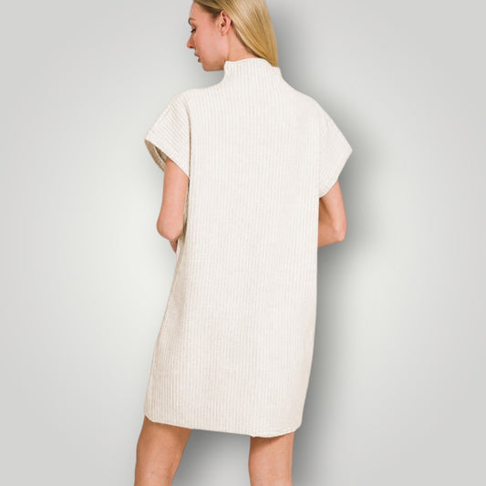 Woman wearing a white ribbed dress against a plain background