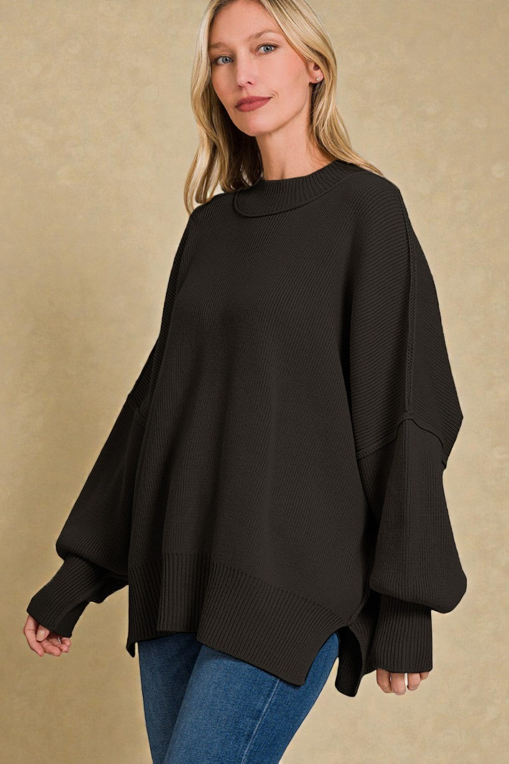 Woman wearing a black sweater over a blue top against a beige background