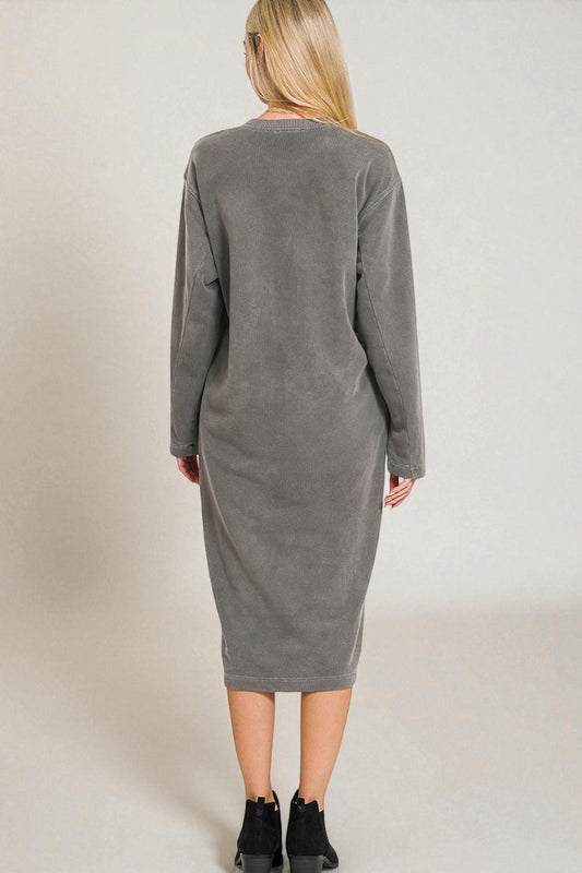 Woman wearing a gray long-sleeve dress against a plain background