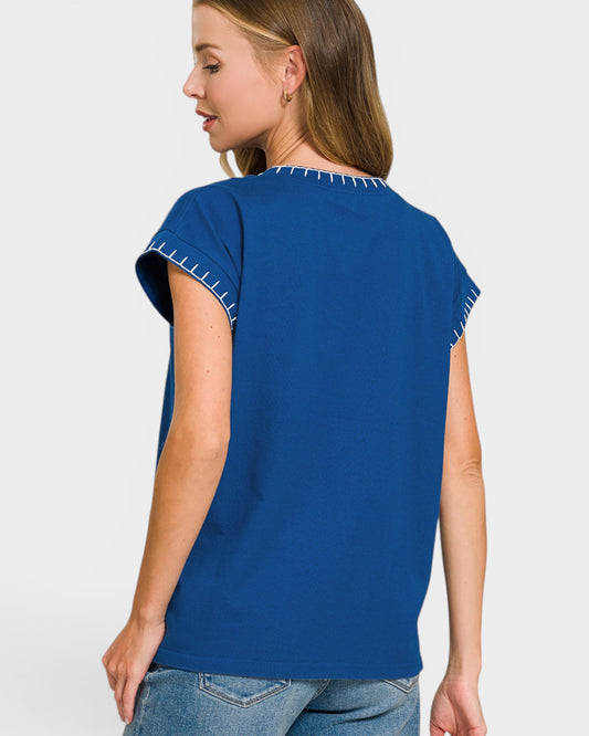 Woman wearing a blue top with white trim on a plain background