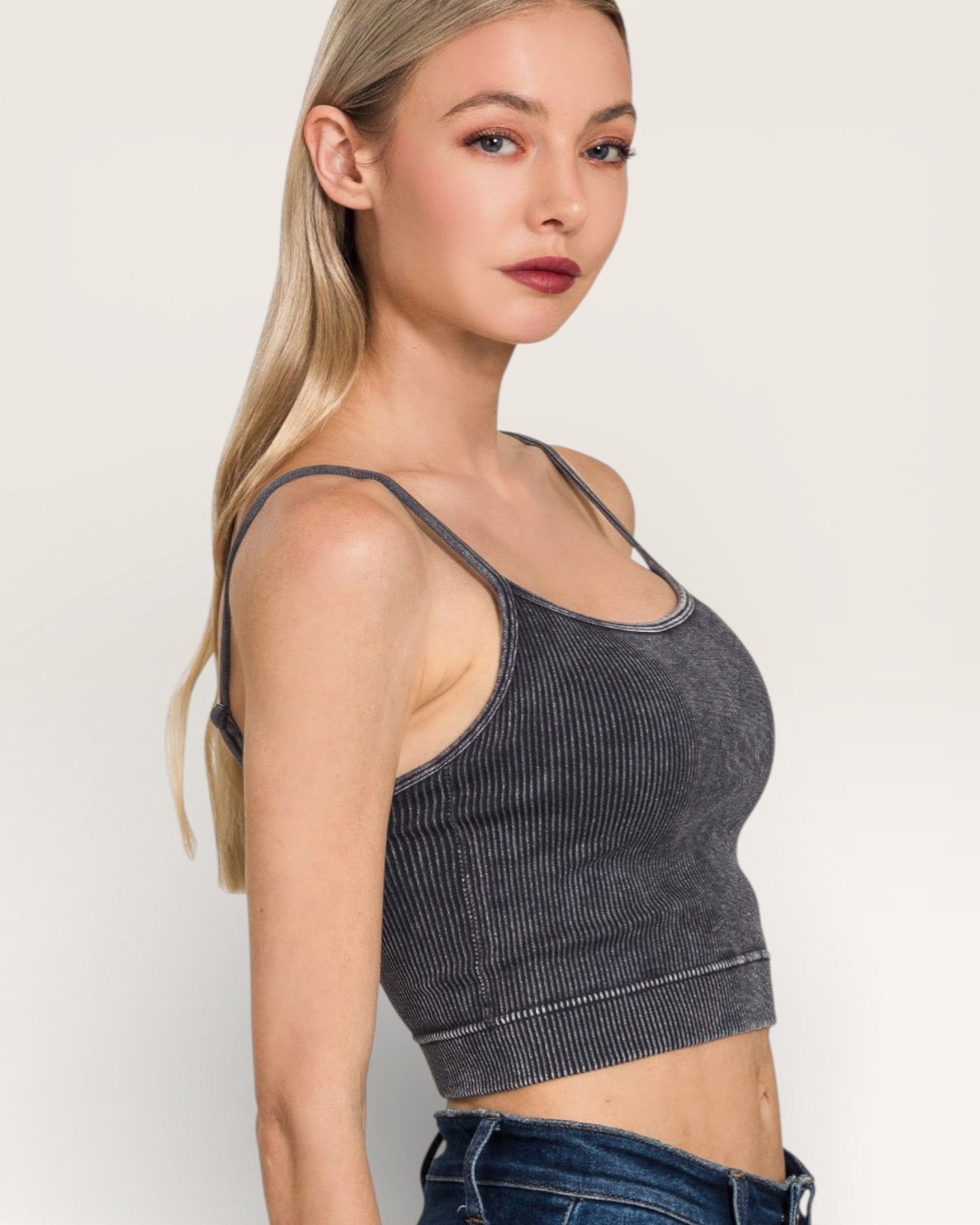 Woman wearing a gray ribbed tank top against a plain background