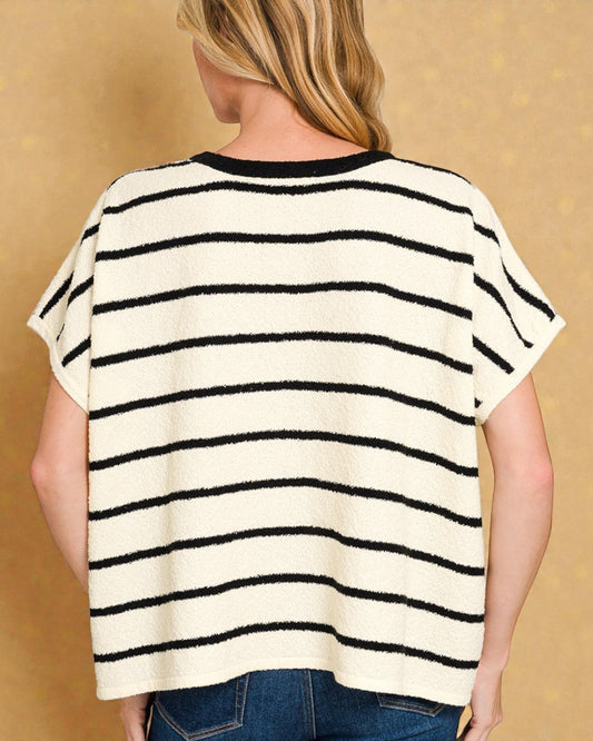 Person wearing a black and white striped sweater against a beige background