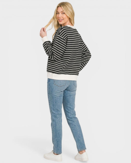 Woman wearing a black and white striped sweater and blue jeans on a white background