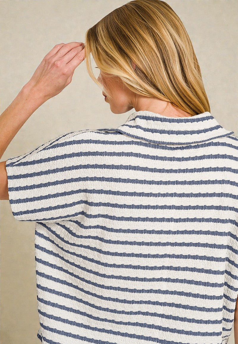 Person wearing a blue and white striped shirt against a beige background