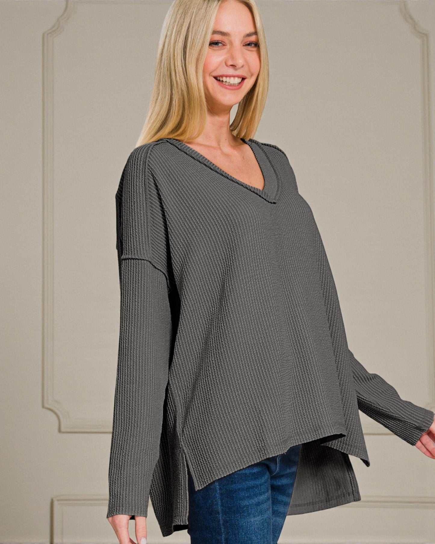 Woman wearing a gray oversized sweater against a neutral background