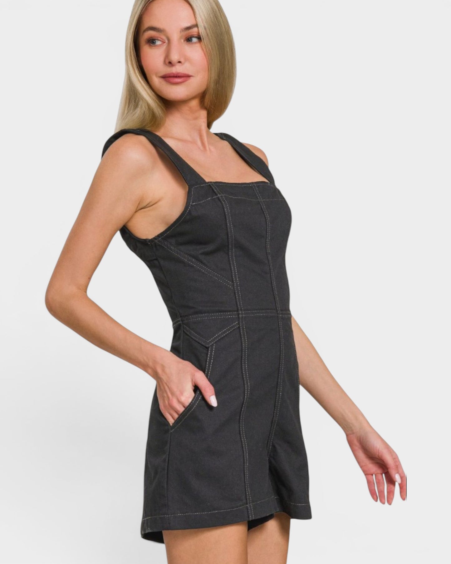Woman wearing a black denim dress against a white background