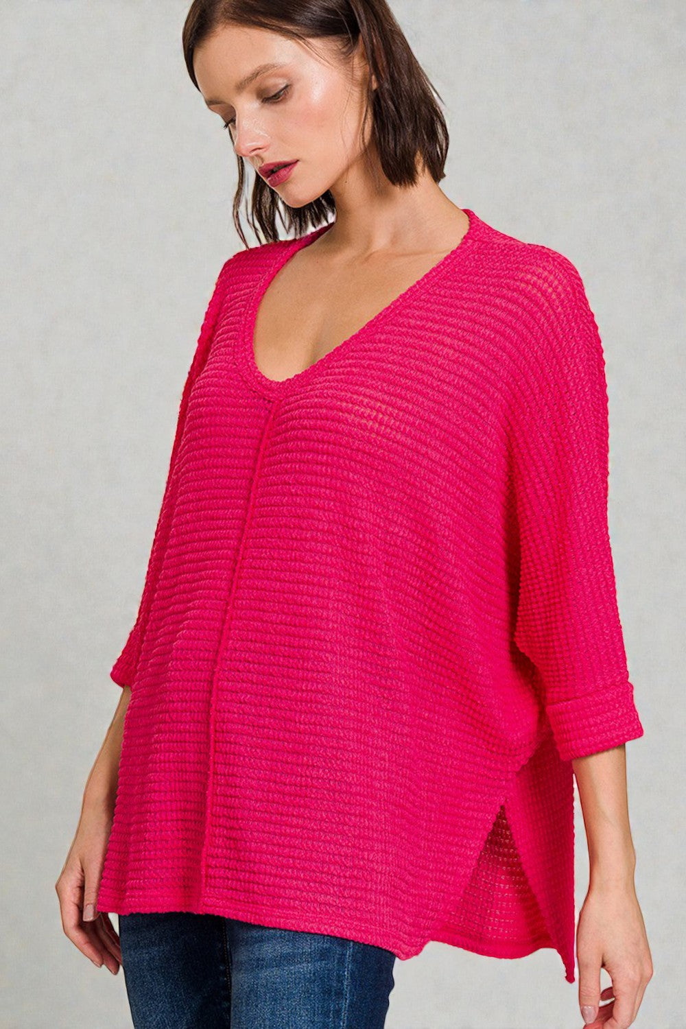 Woman wearing a bright pink textured sweater against a gray background