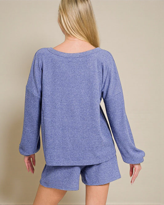Person wearing a blue knit outfit with shorts on a beige background