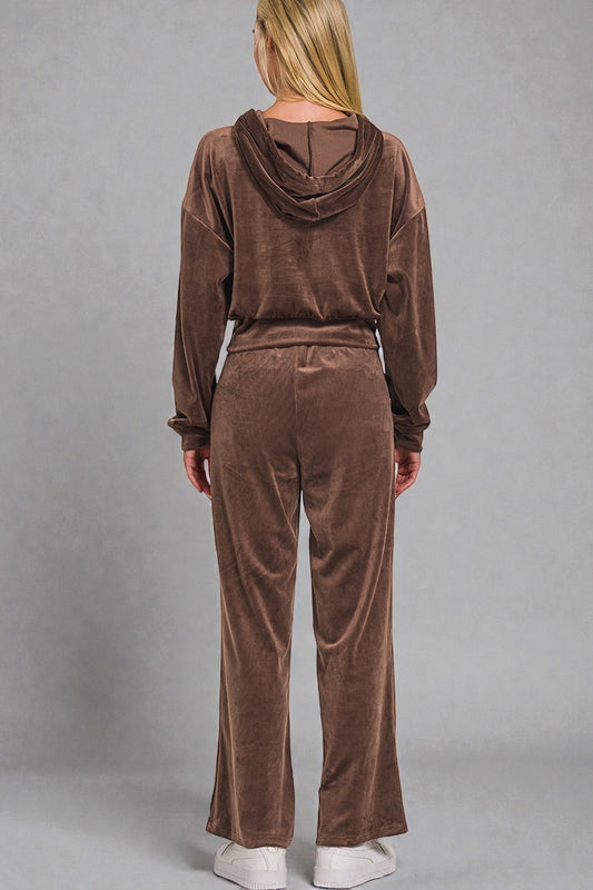 Person wearing a brown velour tracksuit against a gray background