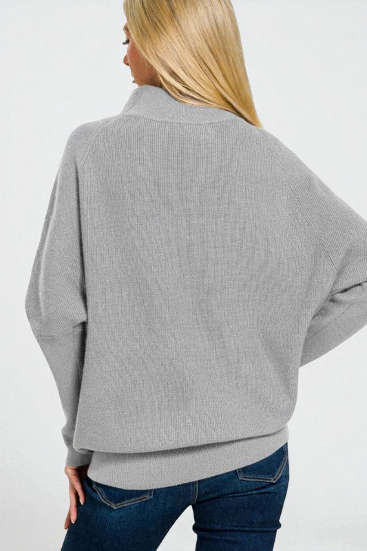 Person wearing a gray sweater and blue jeans on a white background