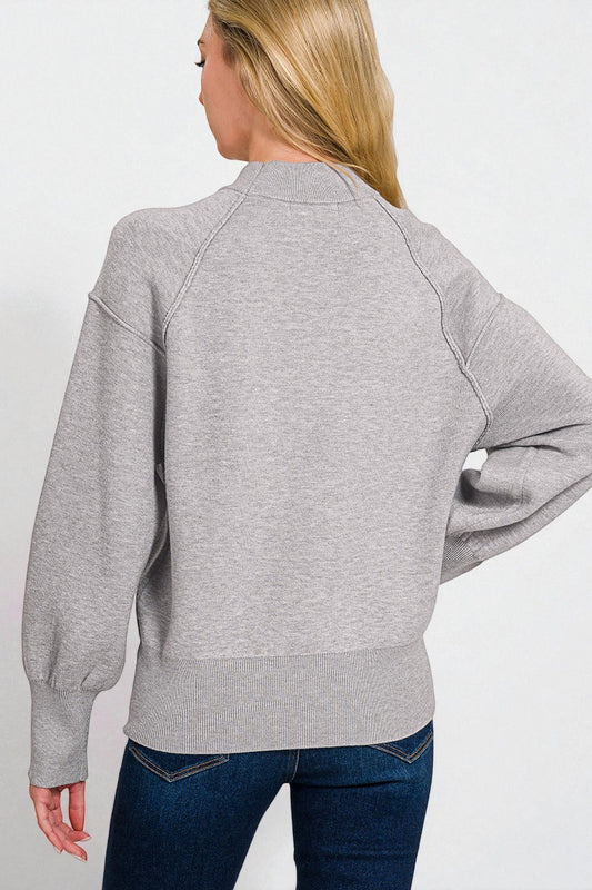Person wearing a gray sweatshirt and blue jeans on a white background