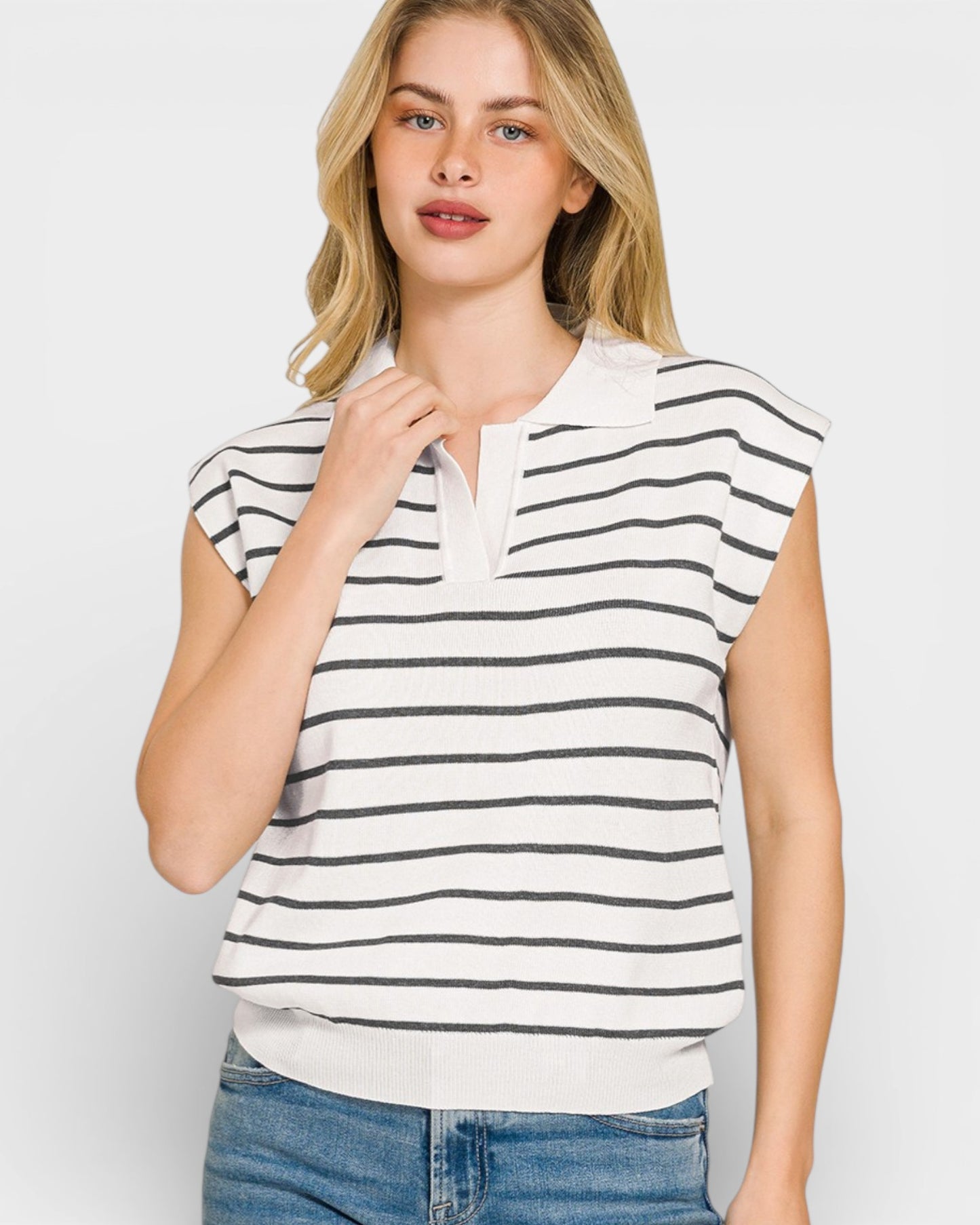 Woman wearing a white and black striped sleeveless top with a plain background