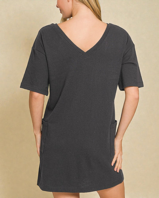 Person wearing a dark gray dress with a plain background