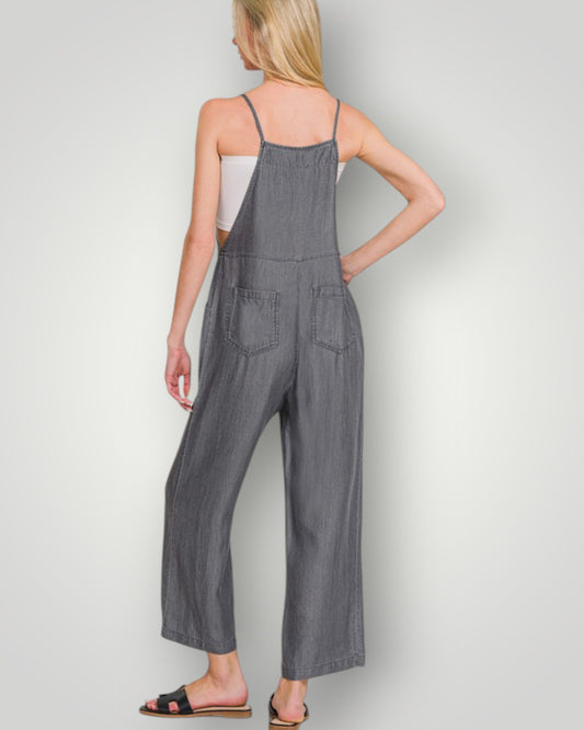 Woman wearing a gray denim jumpsuit on a plain background