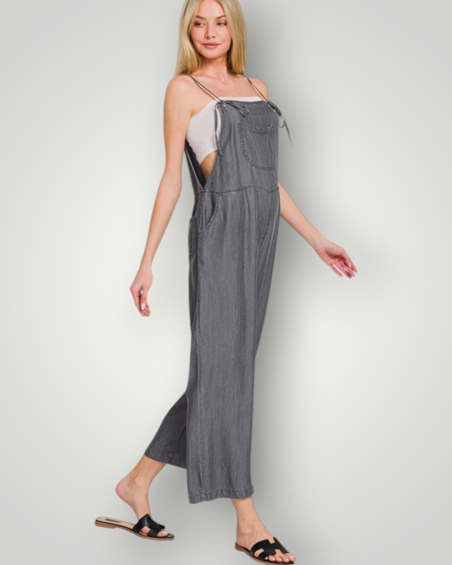 Woman wearing a gray denim jumpsuit on a white background