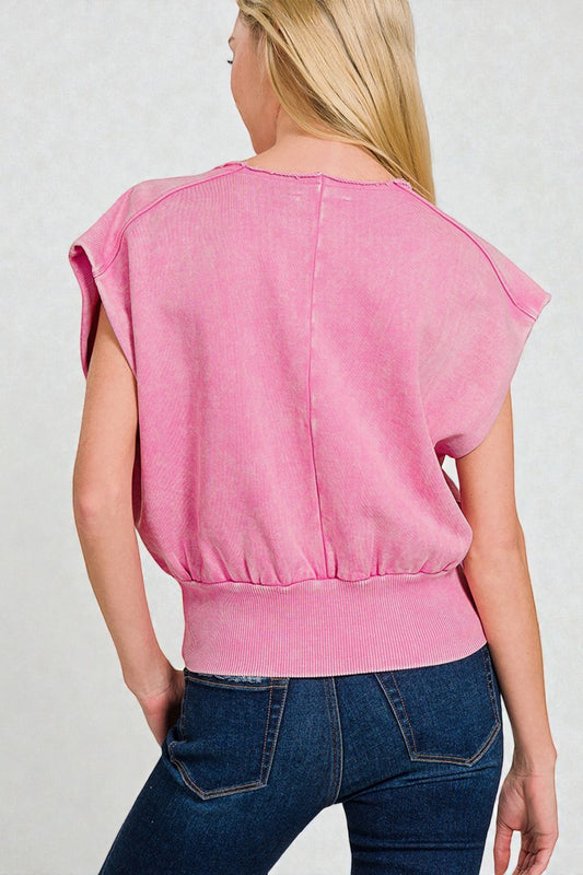 Person wearing a pink sleeveless top and blue jeans on a plain background