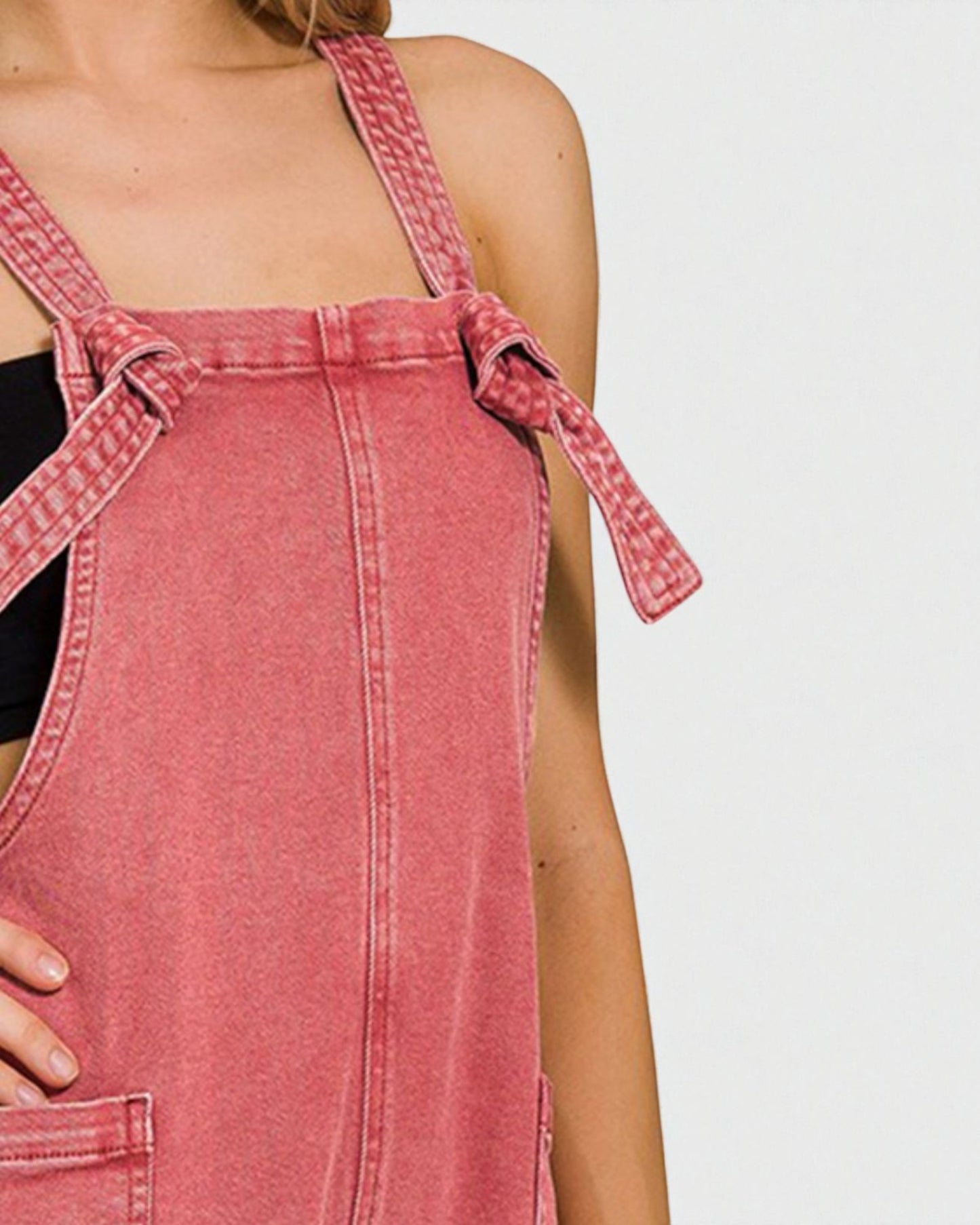 Pink denim pinafore dress on a plain background