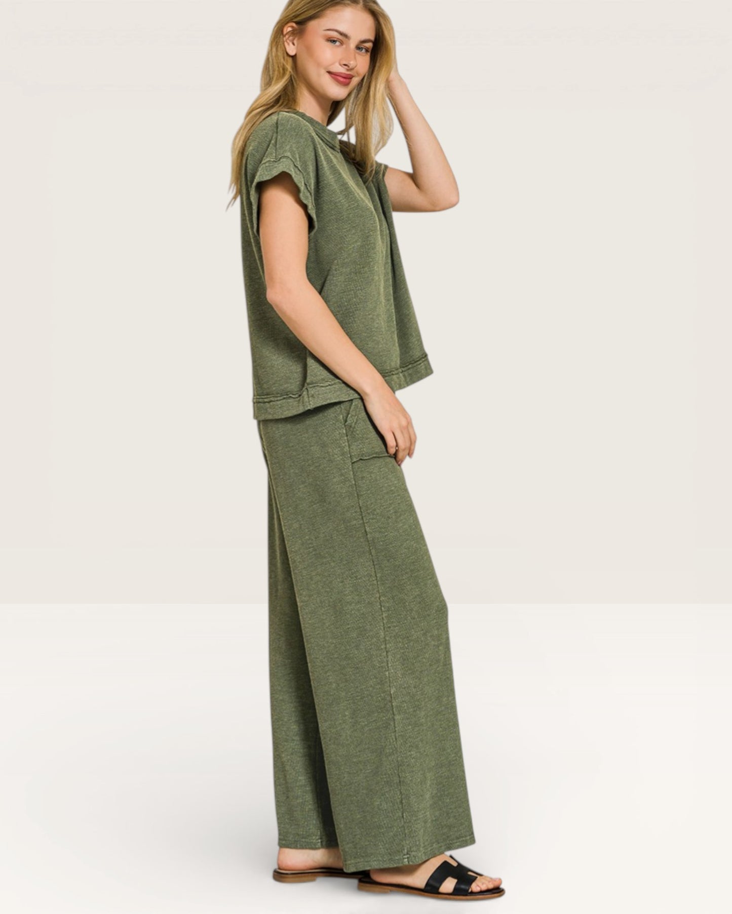 Woman wearing a green outfit with wide-leg pants on a white background