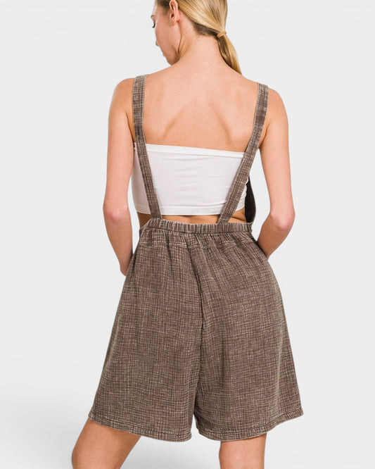 Woman wearing a brown checkered romper with suspenders on a white background