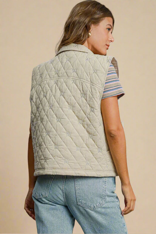 Woman wearing a cream quilted vest over a striped shirt on a beige background