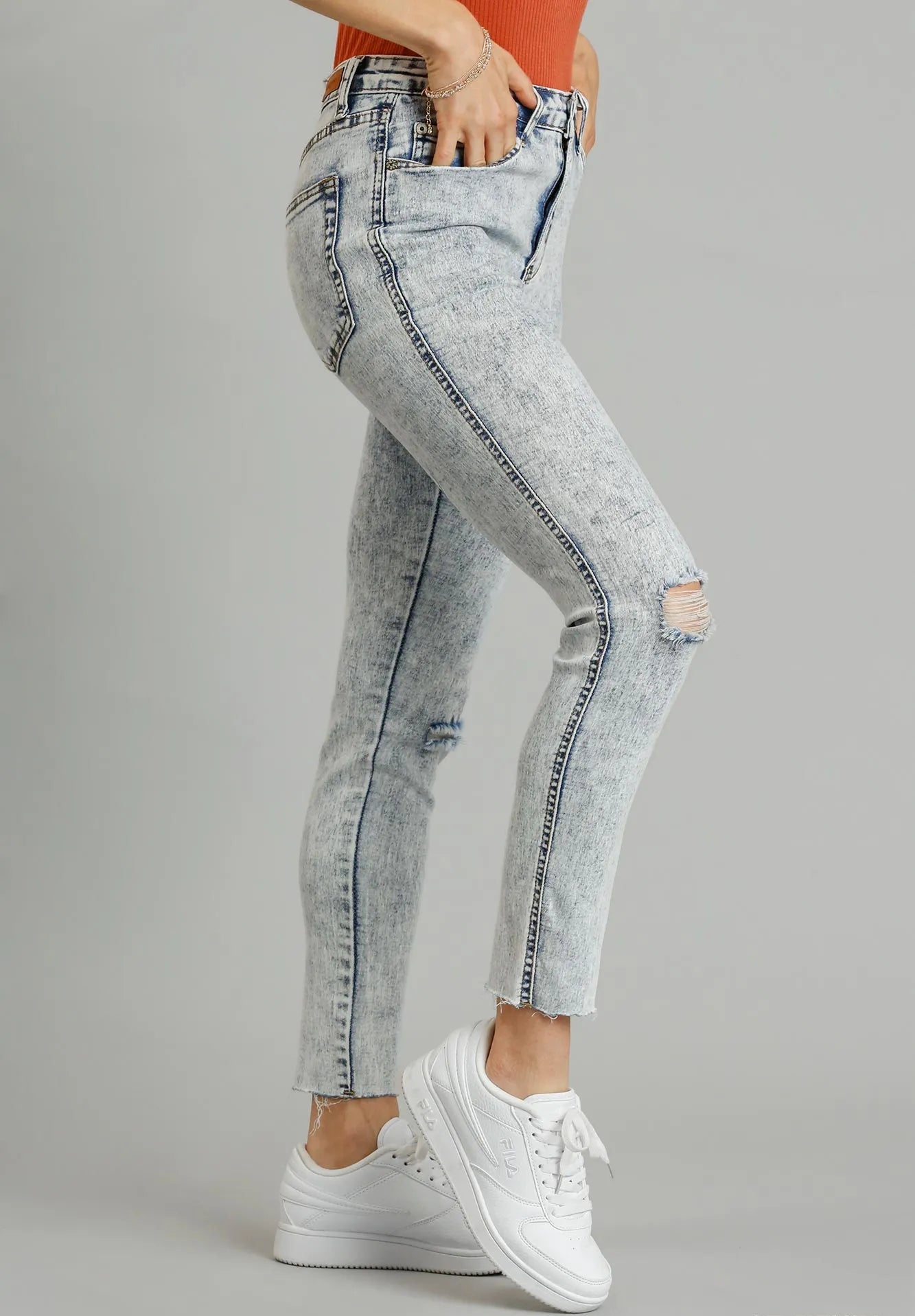 Light denim jeans worn by a person on a gray background