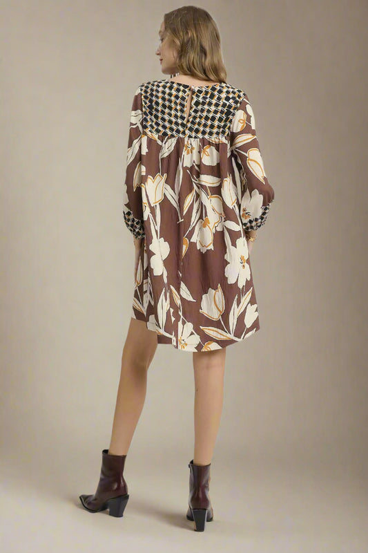 Woman wearing a brown floral dress with a checkered pattern on a white background