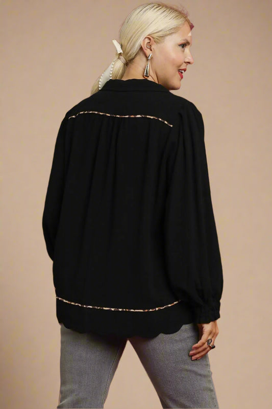 Woman wearing a black top with leopard trim on a beige background