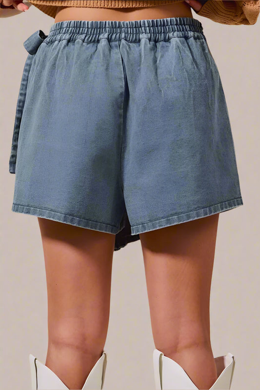 Blue denim shorts worn by a person on a beige background