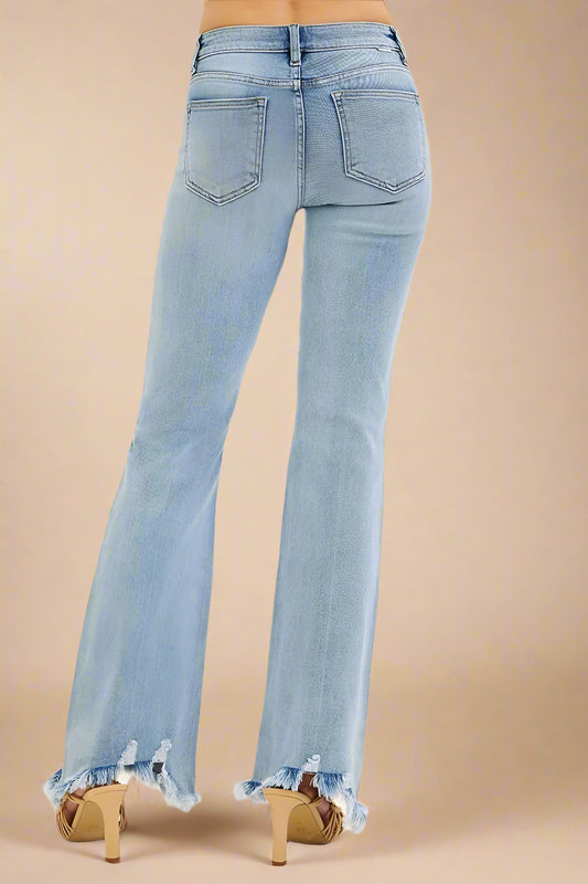 Light blue flared jeans with frayed hems on a beige background