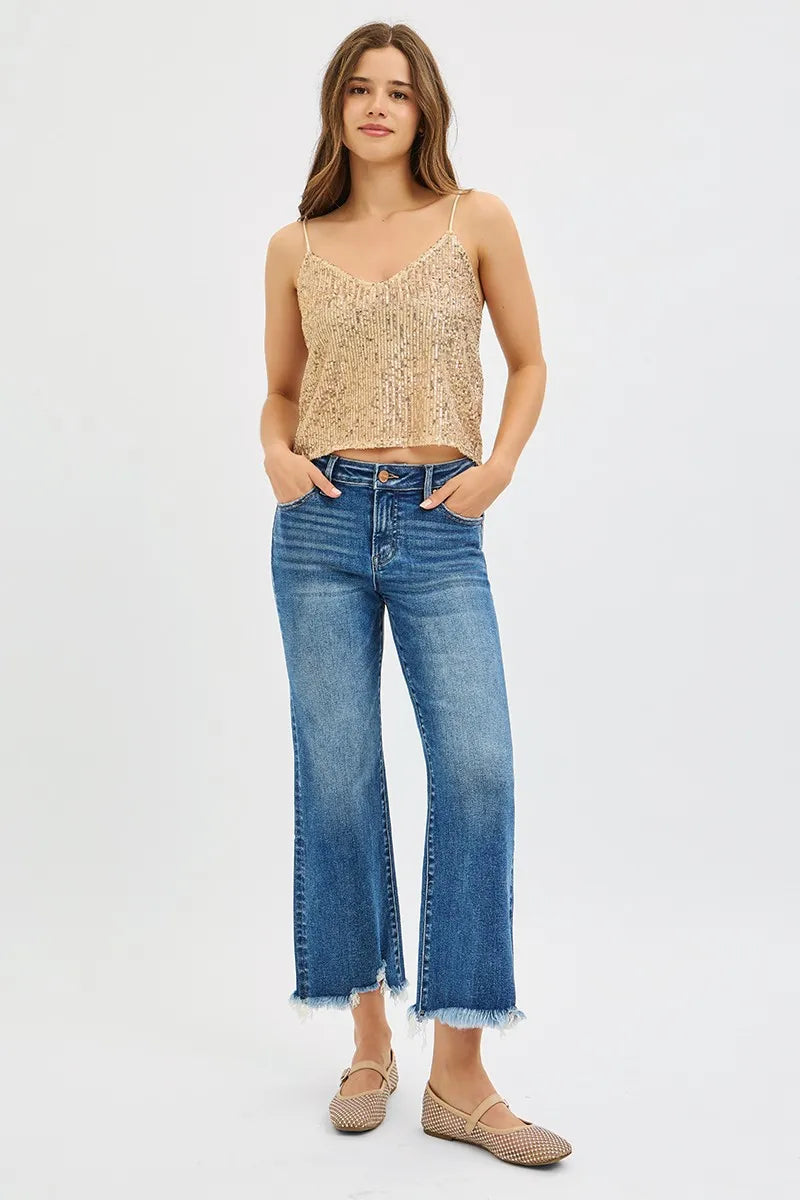 Woman wearing a beige lace top and blue jeans on a white background