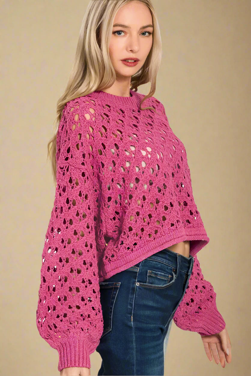 Woman wearing a pink crochet sweater with a white background