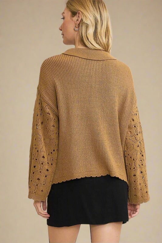 Woman wearing a brown knit sweater with lace details on a plain background