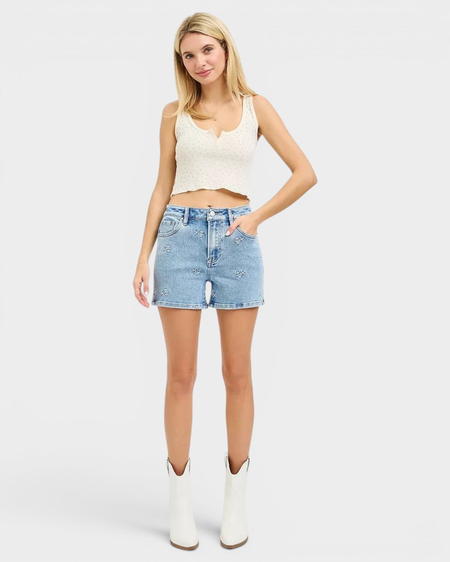 Beach Rose Co. light wash denim shorts with white embroidered floral details, high-rise fit, and short length.