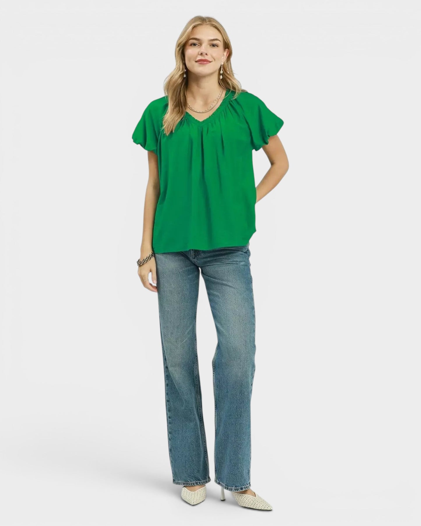 Beach Rose Co. green textured woven blouse with ruffled V-neckline and short puff sleeves, paired with blue jeans.