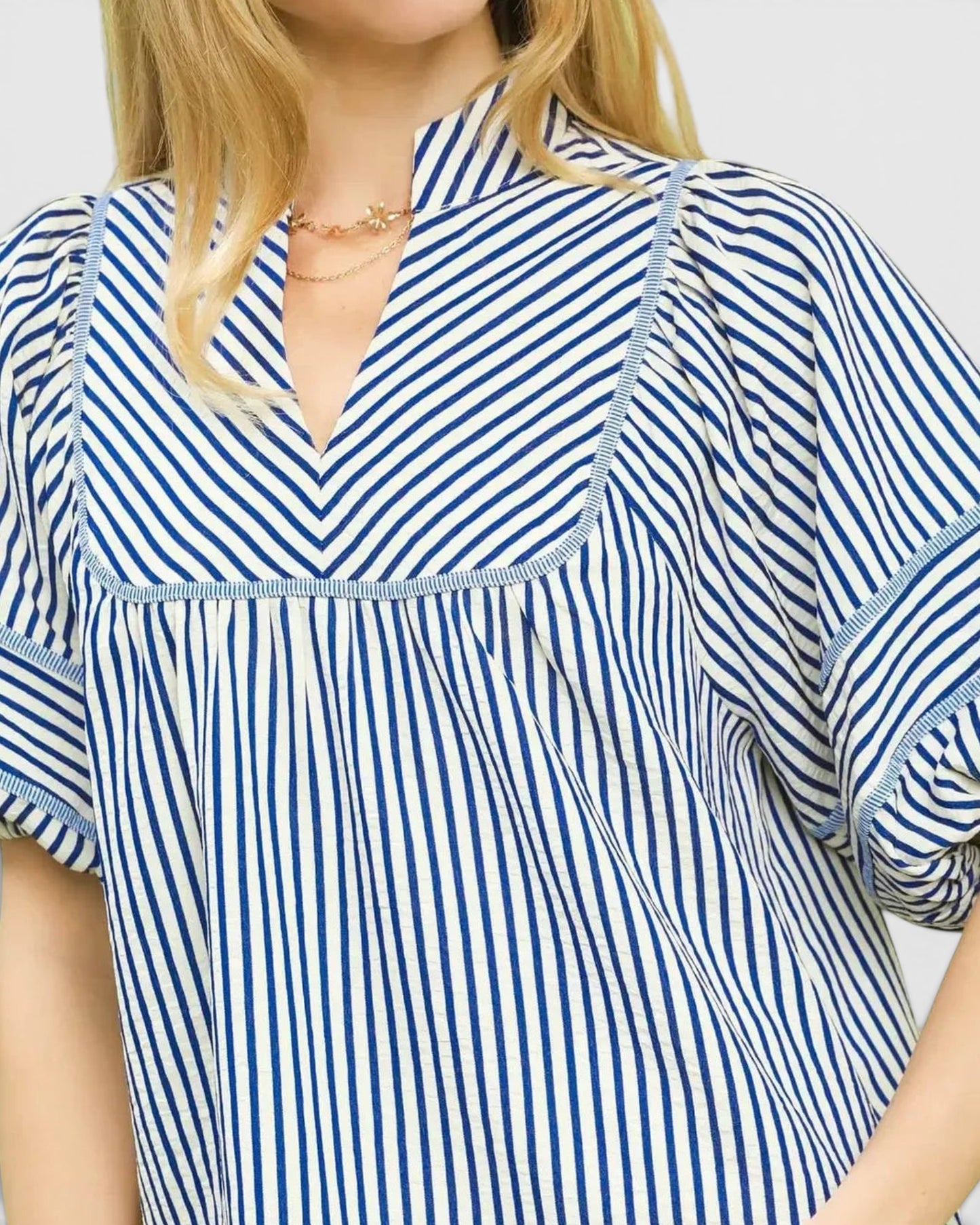 Beach Rose Co. ivory and blue striped puff sleeve top with a v-neck and babydoll silhouette made of cotton and polyester blend.