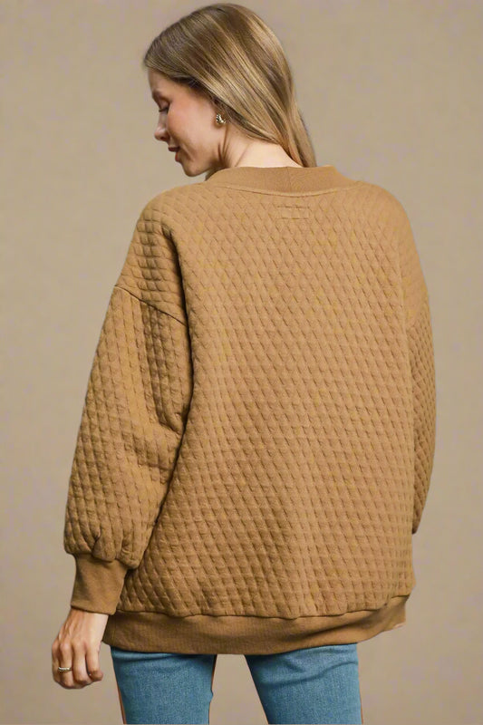 Woman wearing a textured brown sweater on a beige background