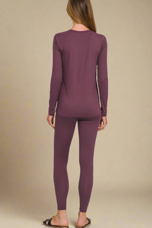 Person wearing eggplant-colored long-sleeve top and leggings on a beige background