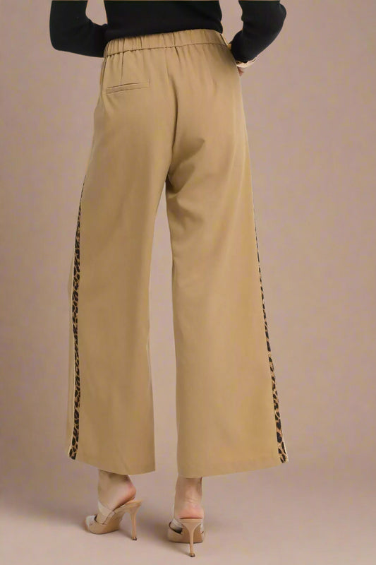 Beige pants with black side stripes on a white background