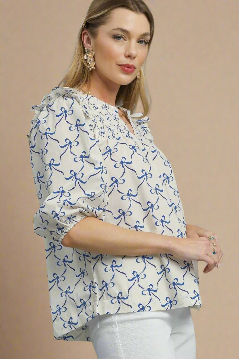 Woman wearing a white blouse with blue floral patterns on a beige background