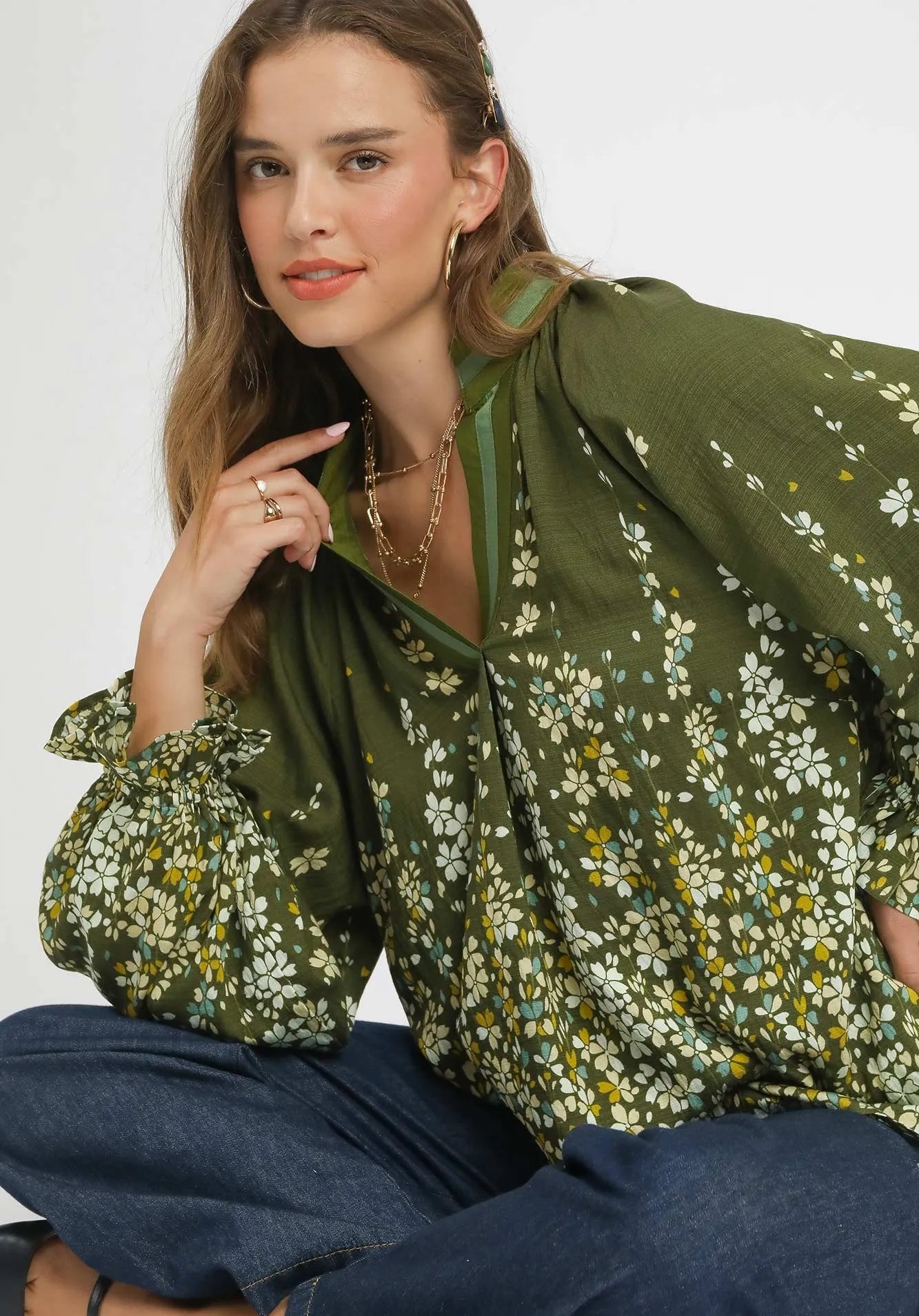 Woman wearing a green floral blouse with a plain background