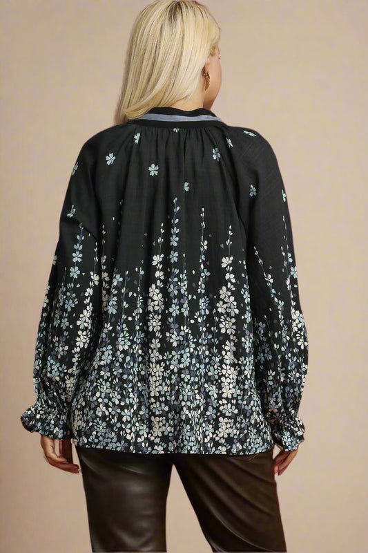 Woman wearing a black floral blouse against a beige background