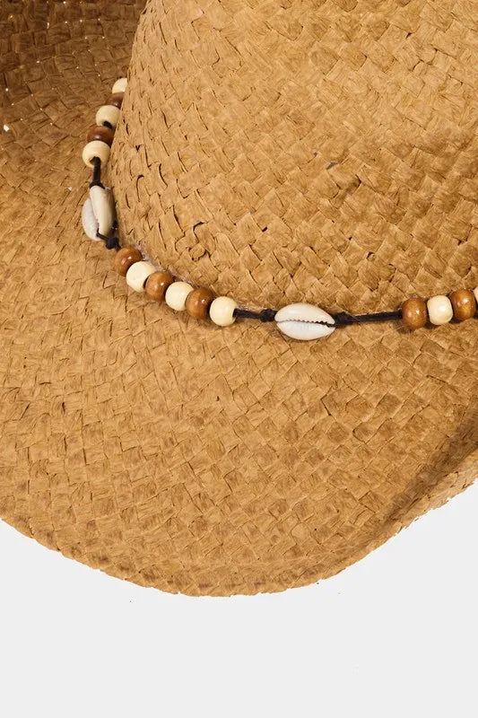 Close-up of a straw hat with a beaded band on a light gray background
