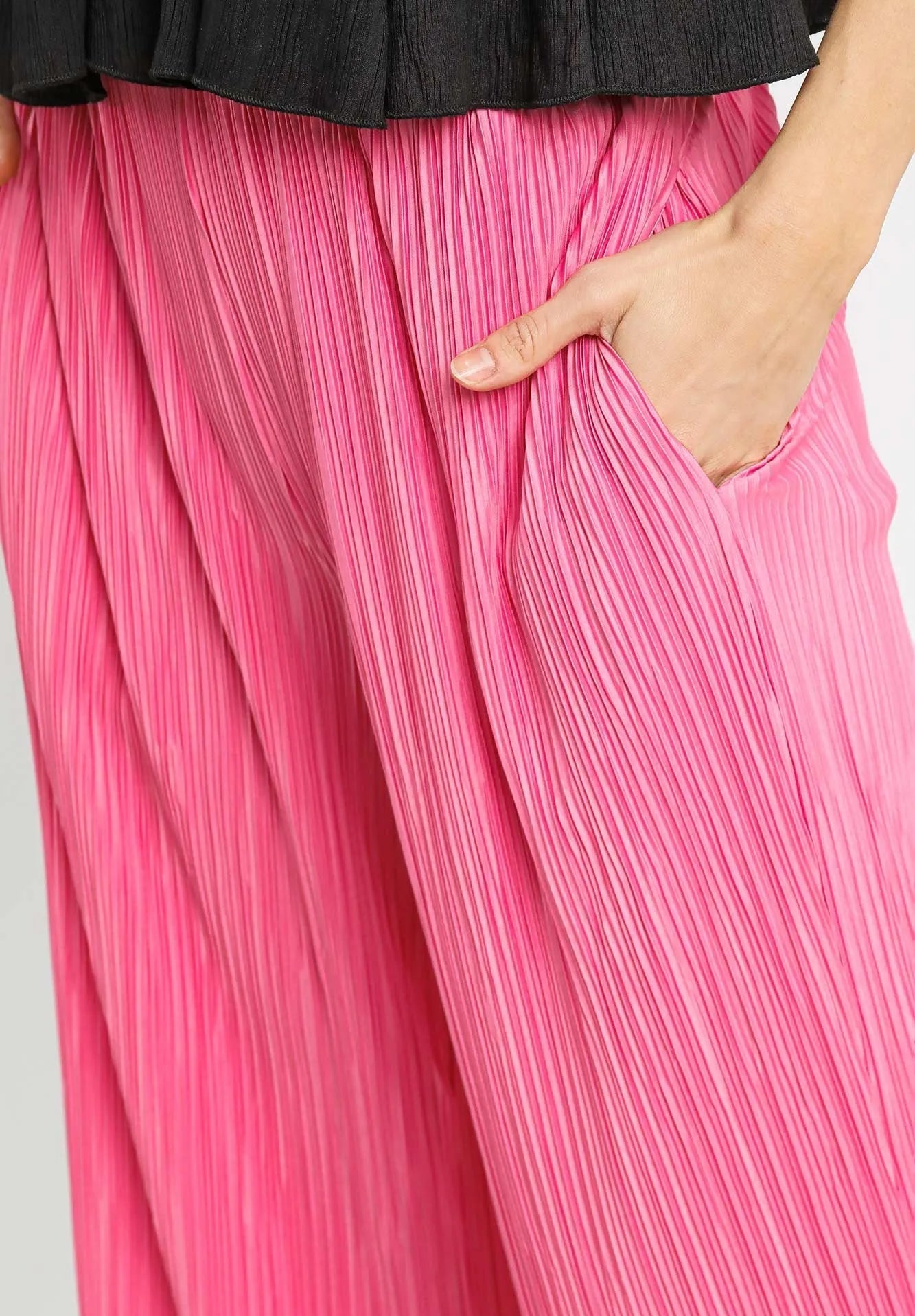 Close-up of pink pleated pants with a black top on a white background