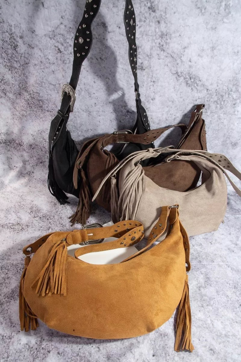 Three suede handbags with fringes on a textured surface