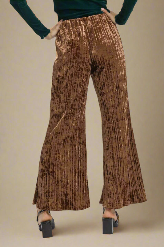 Brown pleated pants worn by a person on a white background