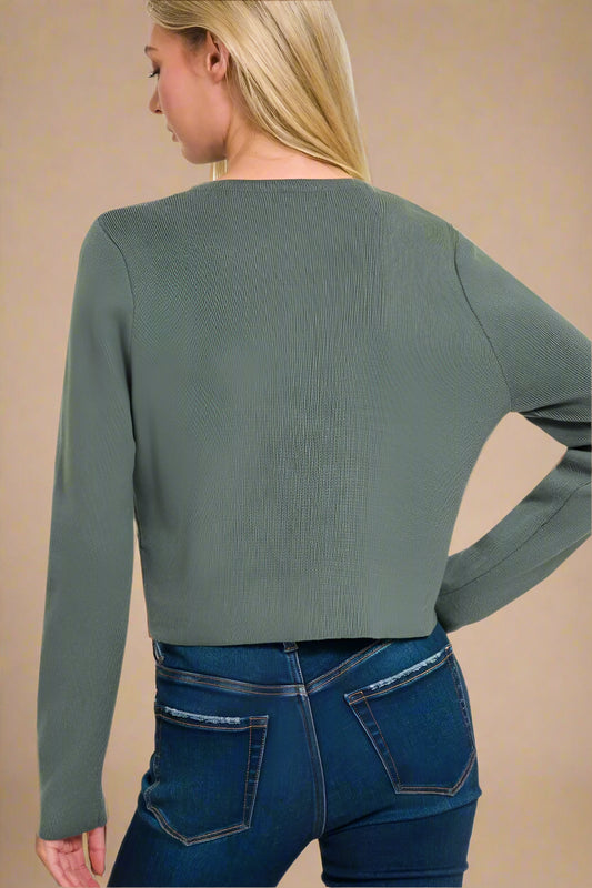 Woman wearing an ash jade sweater and blue jeans on a white background