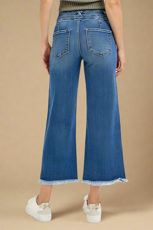 Blue jeans worn by a person on a beige background