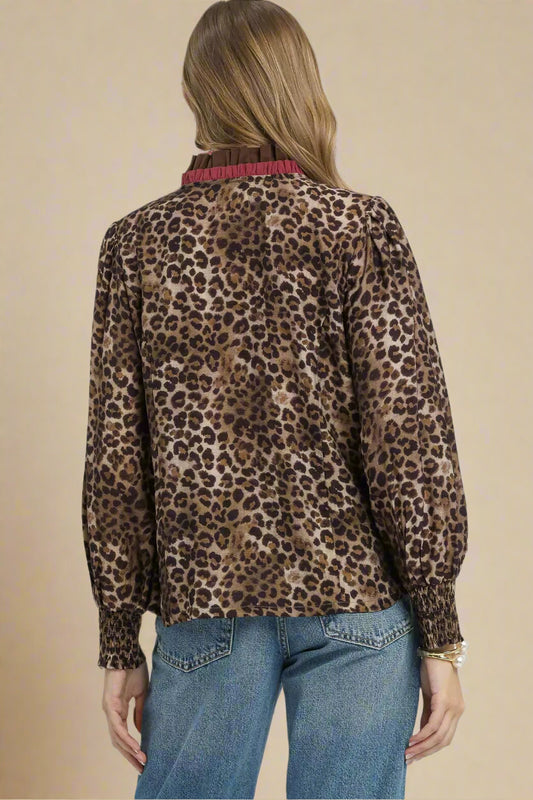 Person wearing a leopard print blouse with a plain background