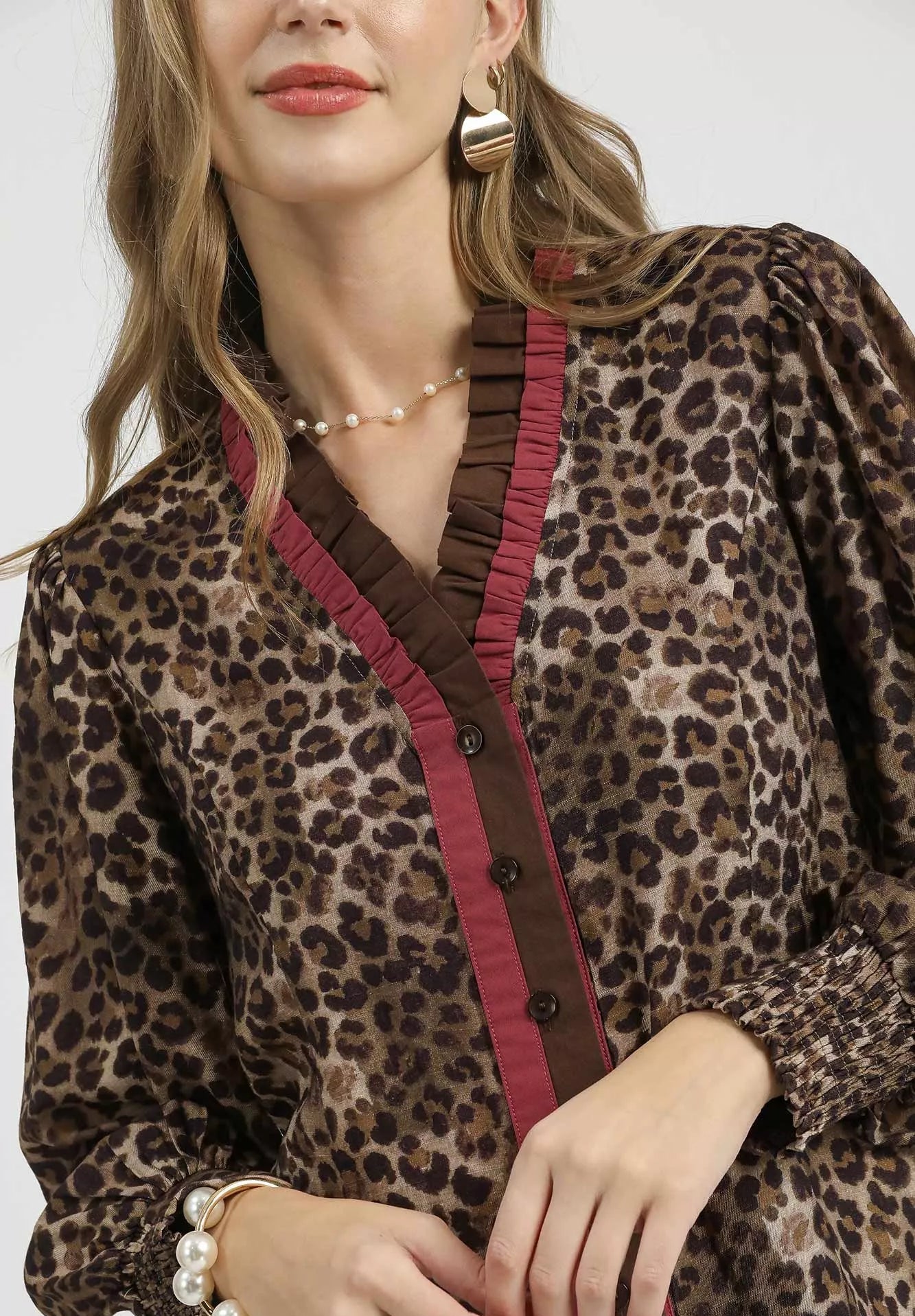 Woman wearing a leopard print blouse with red trim on a white background