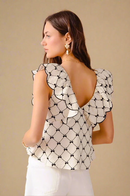 Woman wearing a black and white patterned top with a cactus plant in the background
